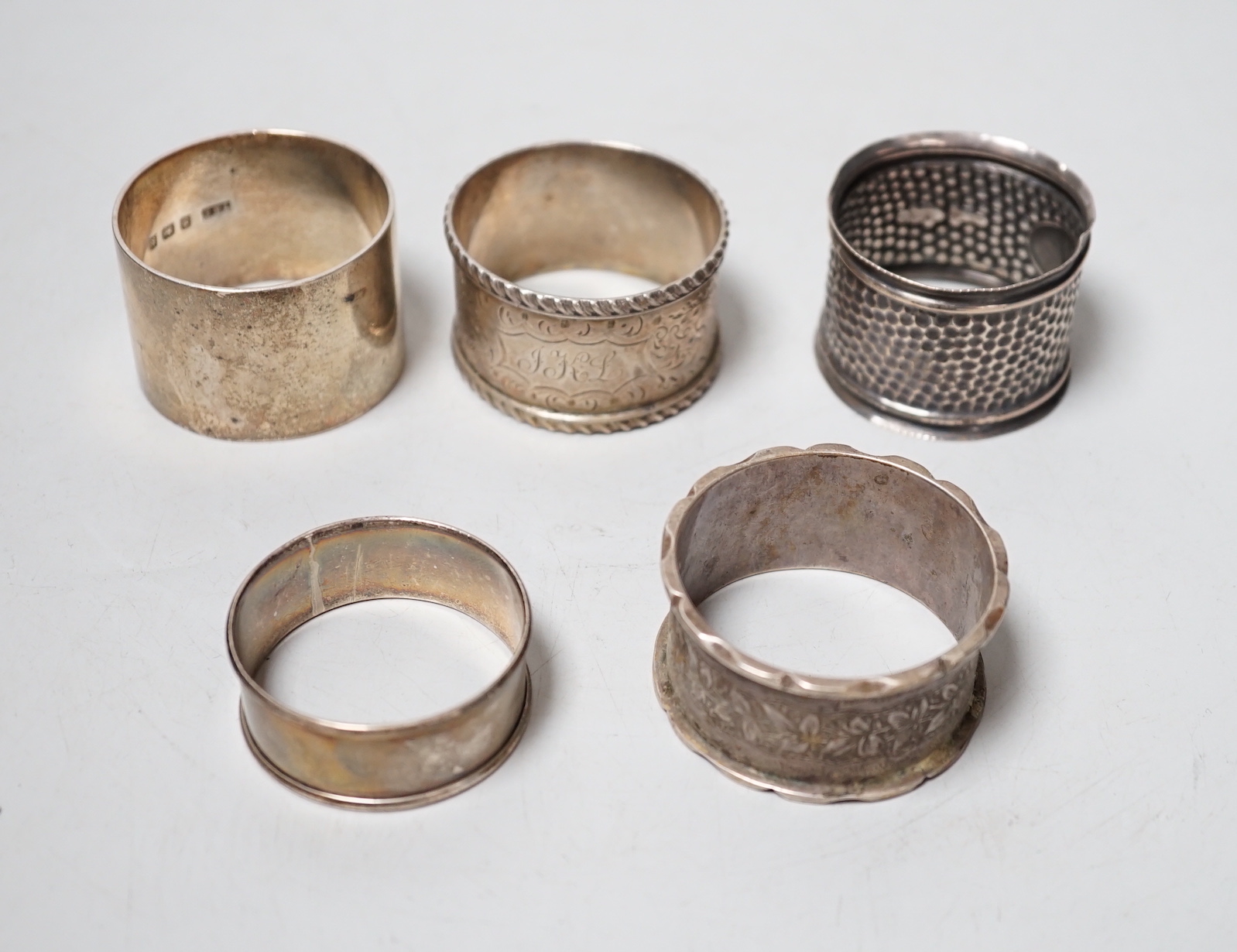 Five assorted silver napkin rings.